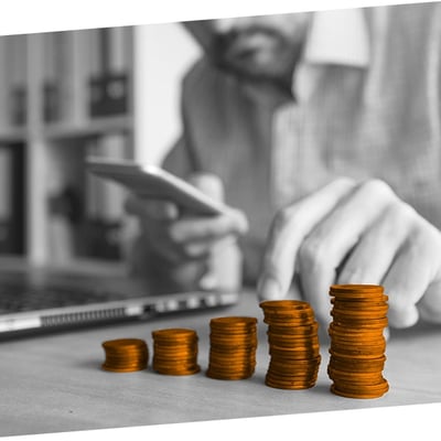 Man sat at a laptop counting stacks of coins
