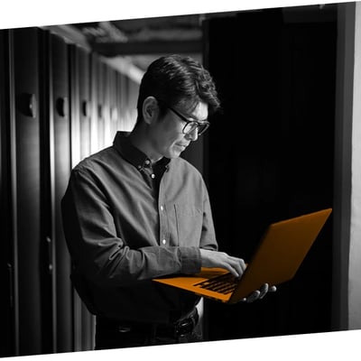 Man working on a laptop within a server room